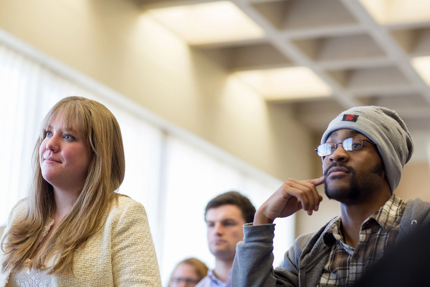 Students sit in class, looking at the professor and listening.